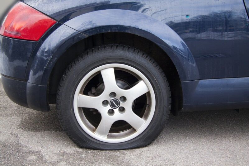 Passenger car with a flat tire parked on a paved surface
