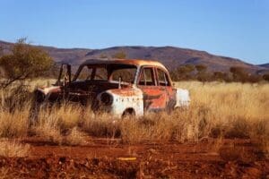 A rusted and gutted abandoned vehicle resting in the open Northern Arizona desert landscape.