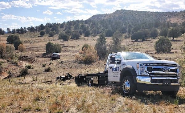 Hoist Off Road Recovery Services flatbed truck preparing to pull a car from a hillside