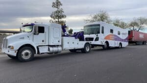 A professional tow truck performing a secure motorhome recreational vehicle towing service.