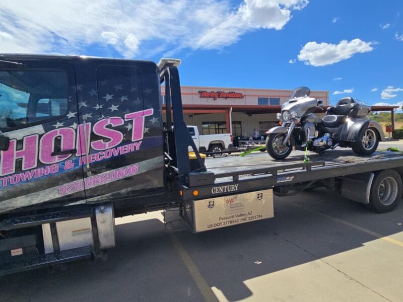 Hoist Towing motorcycle towing service transporting a three-wheel motorcycle on a flatbed tow truck.