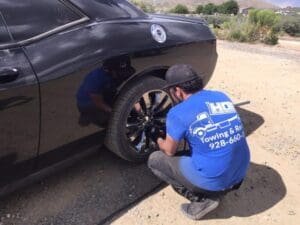 A Hoist Towing driver performing a professional roadside tire change by tightening wheel lug nuts.