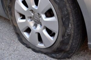 Flat tire showing tread damage caused by driving on it.