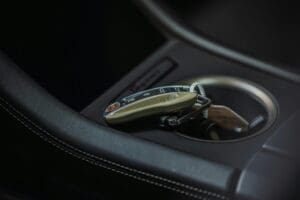 A close-up view of an electronic car key fob left behind inside a vehicle's center console cup holder.