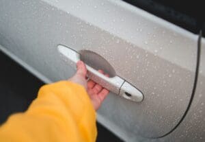 A close-up view of a driver pulling on a locked door handle before calling for professional lockout services.